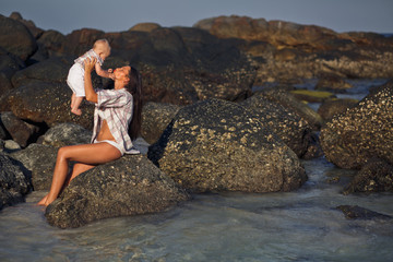 The pretty son with mother  sit on the stones