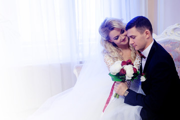 Beautiful young couple, the bride and groom. Sitting on the sofa