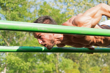Young Athlete Working Out in an Outdoor Gym. Street Workout Exercises. Tense Muscles.