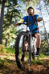 Male mountain biker with bicycle in the forest