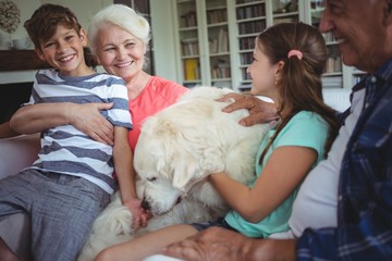 Grandparents and grandchildren sitting on sofa with pet dog