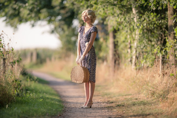 1920s retro fashion woman standing with handbag on rural pathway
