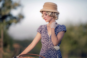 Vintage 1930s fashion woman in blue summer dress standing with b