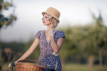 Vintage 1930s fashion woman in blue summer dress standing with b