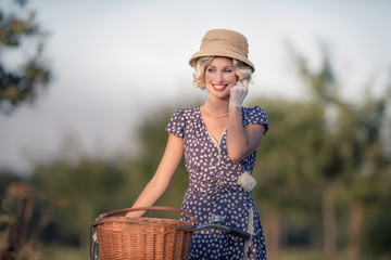 Vintage 1930s fashion woman in blue summer dress standing with b