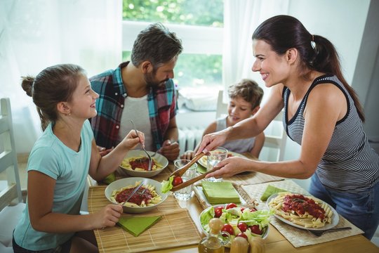 Smiling Woman Serving Meal To Her Family