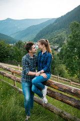 Naklejka na ściany i meble Guy and girl lovers tourists relax and admire beautiful mountain scenery