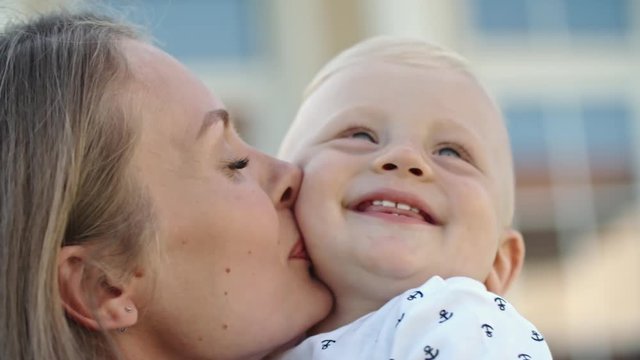 Close up of happy mother kissing her laughing blond toddler 