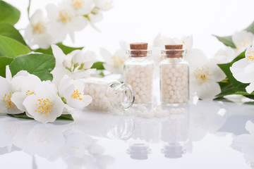Fototapeta na wymiar homeopathic pills with spring flowers on white background 