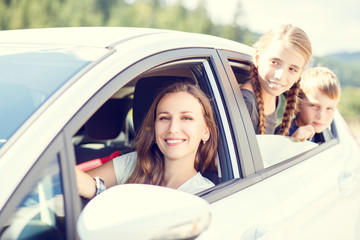 Happy young mom and her children sitting in a car