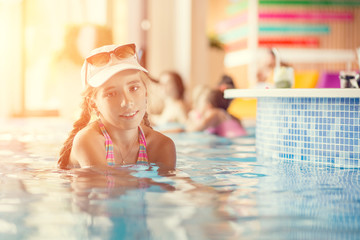 Small teenage girl in hotel resort pool near a bar