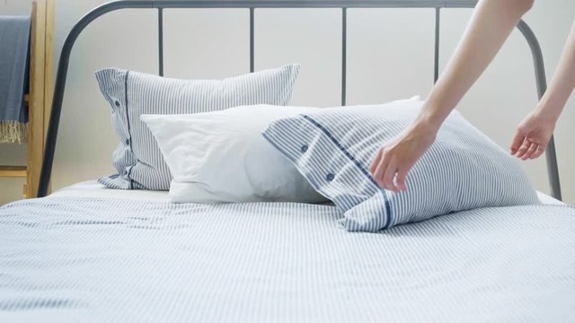 Slow motion video, girl puts soft pillow on her bed
