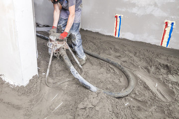 Employee performs sand and cement screed floor.