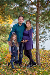 Happy pregnant family in autumn nature