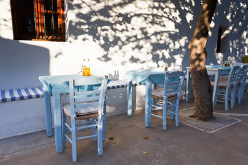 Restaurant tables under a tree with small bottles of olive oil.