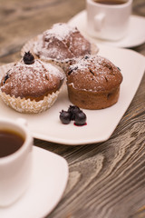 cupcake with berries on a white plate, small white cup of coffee, wooden background