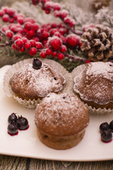 cupcake with berries on a white plate, snowy fir branch on wooden background