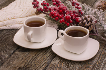 small white cup of coffee, snowy fir branch on wooden background