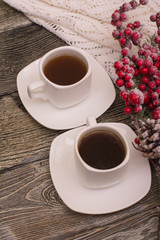small white cup of coffee, snowy fir branch on wooden background