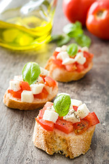 Caprese salad bruschettas isolated on wooden table


