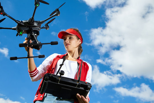 A woman is standing and holding drone