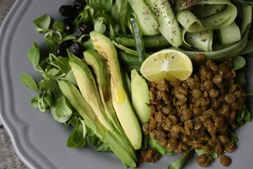 vegan salad with cucumber, lentil, avocado on a gray plate. healthy eating every day.