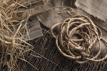 Still life of ropes, boards, burlap and hay in the old wooden table.