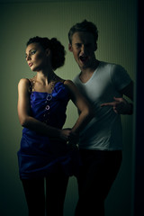 Funny man stands behind seductive woman in blue dress