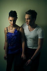 Agressive woman in blue dress stands behind man in white t-shirt