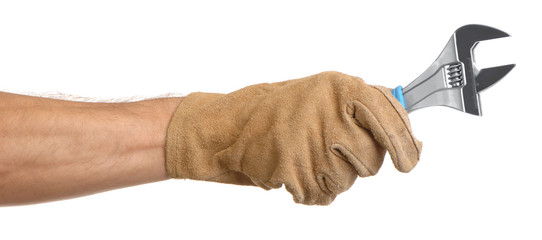 Man's hand and arm in leather work glove holding adjustable wrench tool isolated on white...