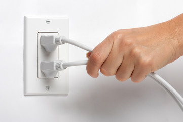 Woman pulling yanking unplugging electrical plugs cords from household wall power outlet isolated...