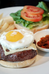 Burger with fried egg, cheese, tomato and vegetable