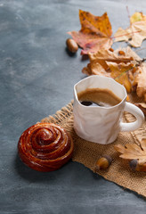 Hot coffee in mug with cinnamon bun