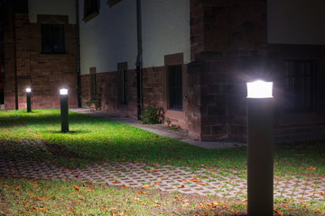 Outdoor lights (lanterns, bollards) in front of an old administration building illuminating a...