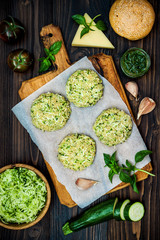 Raw ingredients for vegetarian dinner recipe. Preparing veggies cutlets or patties for burgers. Zucchini quinoa veggie burger with pesto sauce and sprouts. Top view, overhead, flat lay