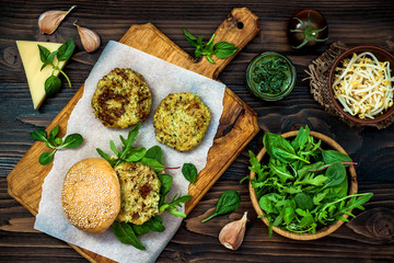 Zucchini quinoa veggie burger with pesto sauce and sprouts. Vegetarian burger on a cooking sheet ready to prepare hamburger. Top view, overhead, flat lay