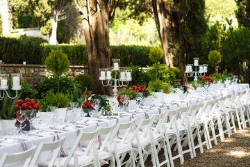 Long dinner table with white candleholders and red tomatoes stan
