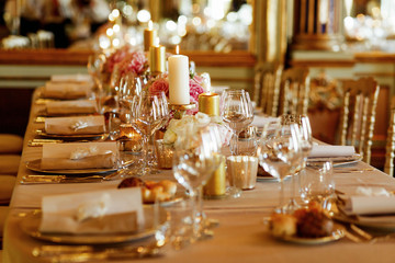 Fototapeta na wymiar Glassware sparkles on dinner table served in golden and pink ton
