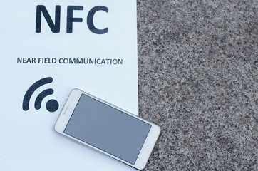 close up white mobile phone nfc near field communication on the backgroung of gray stone slab 