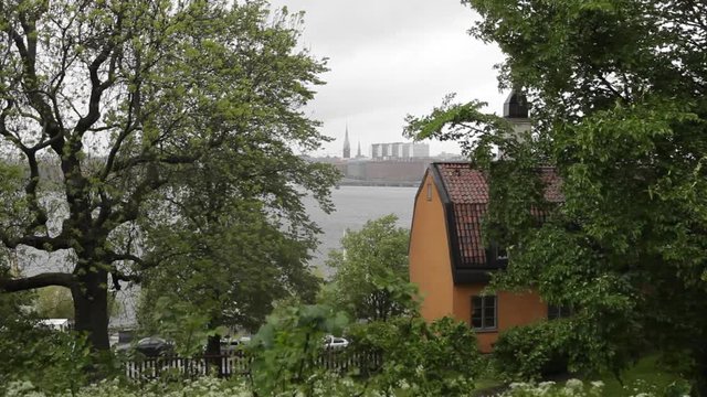 Stockholm view with some trees and a house in the foreground. The wind shakes the trees.