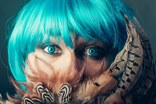 Man in blue wig behing feathers