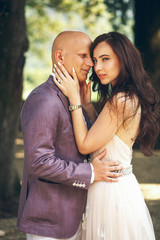 Sensuous bride holds groom's head tender while he hugs her waist