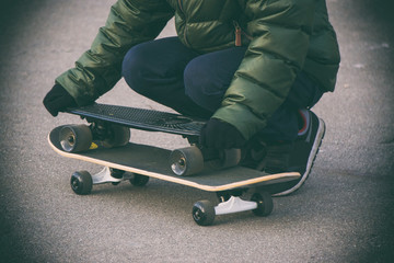 boy on a skateboard, two black skateboard green jacket