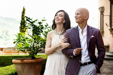 Handsome bald-headed man leads pretty woman around the garden