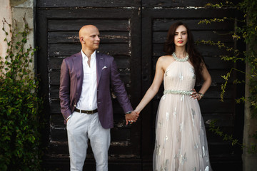 Rich wedding couple stands before black wooden doors