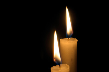 Two burning candles on black background. Copyspace
