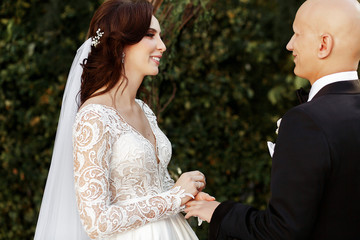 Perfect bride smiles tender to groom holding his hand during the
