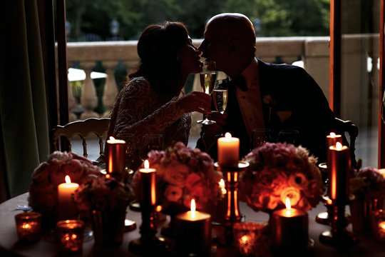 Dark picture of wedding couple kissing at the table full of cand