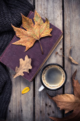Old book, knitted sweater with autumn leaves and coffee mug