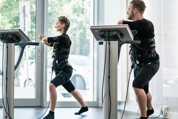 Two sportive people having training session in EMS studio gym